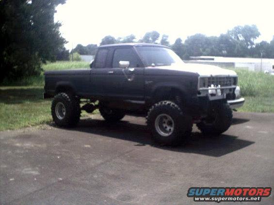 Lifted dark-colored pickup truck with large tires parked on pavement