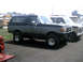 1996 Ford Bronco - A two-tone Ford Bronco is parked next to another truck, with school buses visible in the background.