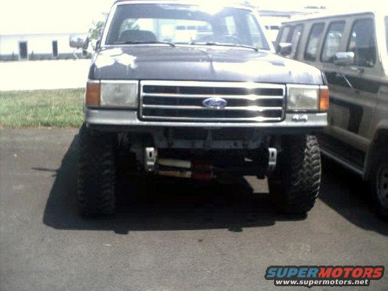 Front view of lifted dark gray truck with winch, next to another vehicle