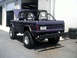 1996 Ford Bronco - This modified Ford Bronco features a roll cage and custom rear bumper, with its hood up in front of a garage.