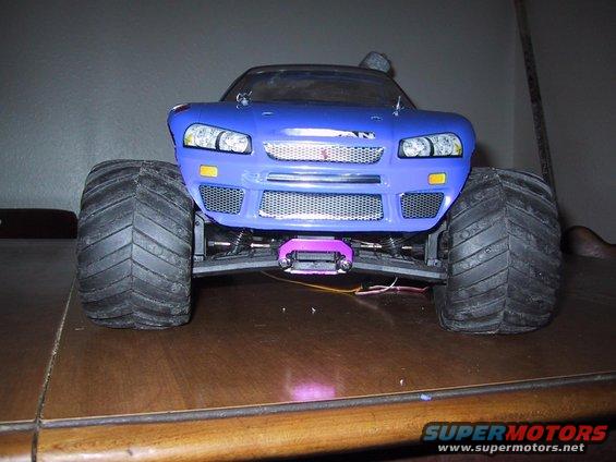 Blue monster truck front view with large tires and mesh grille