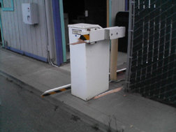White automatic gate opener next to a chain-link fence