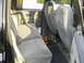1990 Chevrolet Suburban - The interior of a 1990 Chevrolet Suburban features grey corduroy seats and door panels, with a jack visible on the floor.
