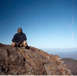 1979 Ford Ranchero - A person sits on a rocky ledge overlooking a vast, hazy landscape under a bright blue sky.