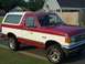 1988 Ford Bronco - This two-tone Ford Bronco is parked in front of a suburban house with a wooden fence.