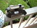 1969 Ford Mustang - A brake caliper and slotted rotor are shown resting on a white railing outdoors.