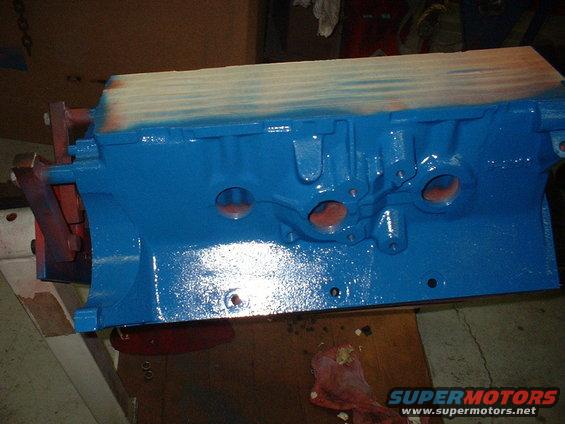 Blue painted engine block on a workbench, with red mounting brackets