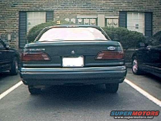 Dark sedan parked in a lot, rear view. White license plate area visible