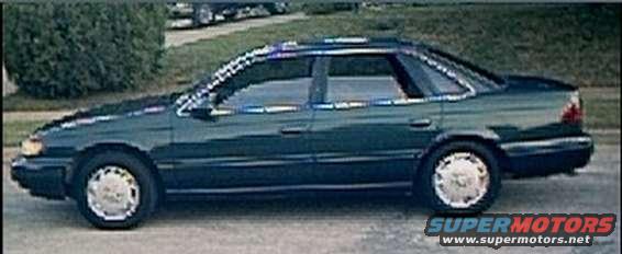 Dark green sedan parked on a street. It has a sunroof and alloy wheels