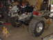 1969 Ford Bronco - A vehicle chassis is undergoing repairs or modifications in a workshop setting, with the engine and large tires installed.