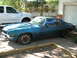 1970 Chevrolet Camaro - A weathered blue coupe sits in a driveway next to a white pickup truck, showing signs of rust.