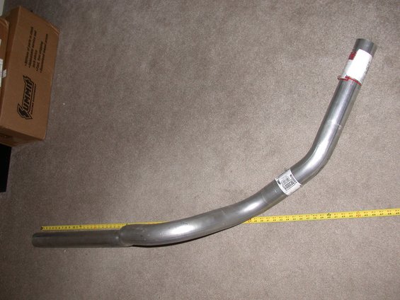 Exhaust pipe with Summit Racing box and yellow measuring tape on carpet