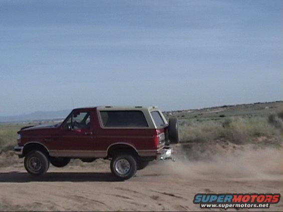 Red 1994 Ford Bronco kicking up dust on a dirt road