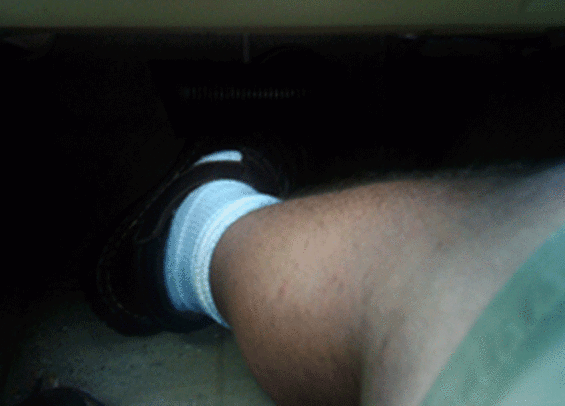 Close-up of a white and blue striped sock on a person's foot inside a car