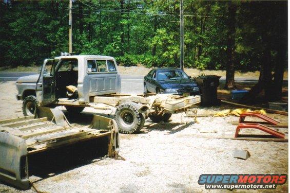 Ford truck cab and chassis sitting outside, with a car in the background