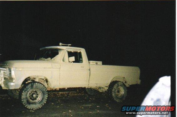 1979 Ford F-250 pickup truck covered in mud, parked at night