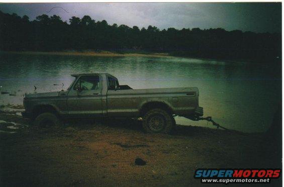 1979 Ford F-250 stuck in mud next to a lake, being pulled by a chain