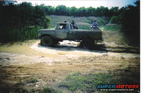 Gray 1979 Ford F-250 stuck in mud with people on ATVs behind it