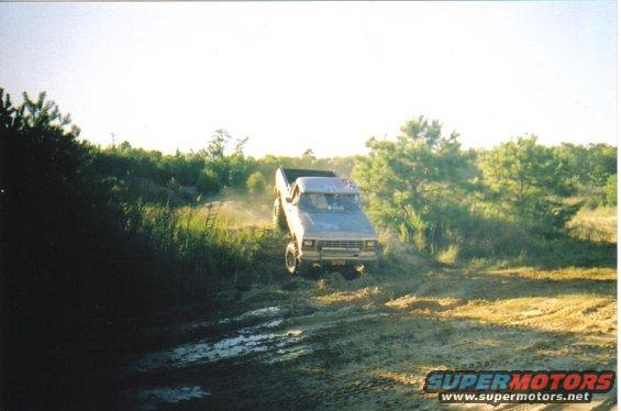 Light blue 1979 Ford F-250 driving through mud and dirt off-road