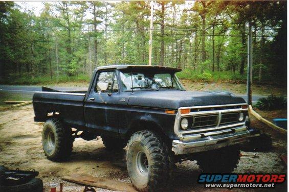 Black Ford F-250 truck with large tires, parked outdoors. Front 3/4 view