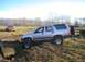 1978 Ford Bronco - A silver Toyota 4Runner navigates a muddy obstacle course, with another vehicle visible in the distance.