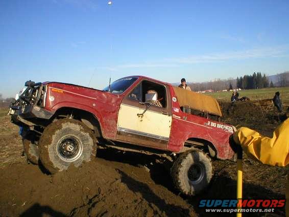 1978 Ford Bronco with large tires on a muddy hill. Text on the side reads '2 BIG BRONCOS'