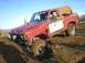 1978 Ford Bronco - This red SUV is stuck in the mud, with a driver and passenger visible. The windshield has club text.