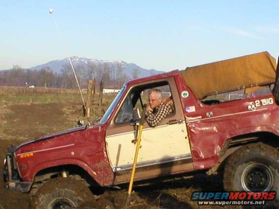 Red and white 1978 Ford Bronco with a man driving, side view