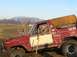 1978 Ford Bronco - A man drives a red and white 1978 Ford Bronco off-road, with mountains in the background.