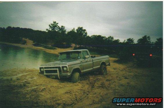 Ford F-250 stuck in mud near water, another vehicle visible in background
