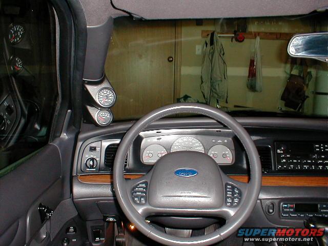 2002 Ford Crown Victoria interior showing dashboard, steering wheel, and aftermarket gauges