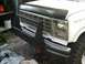 1986 Ford Bronco - The front end of a white Ford truck, likely from the early 1980s, is equipped with a heavy-duty bull bar.