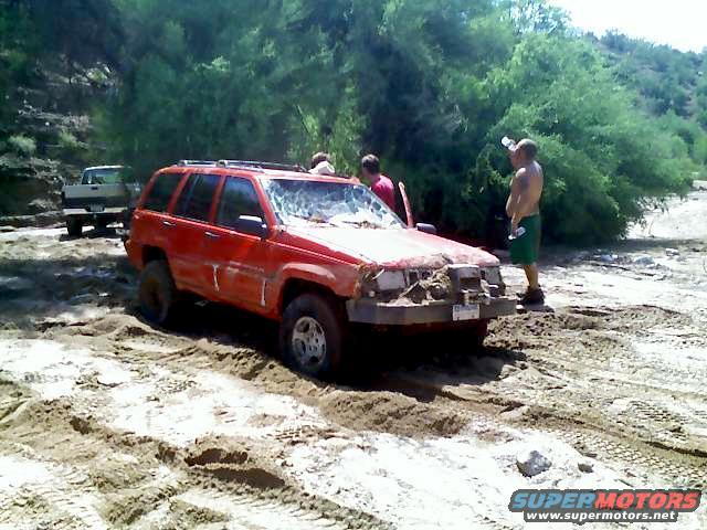 red Jeep Grand Cherokee stuck in sand, another truck in background