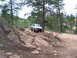 1978 Ford Bronco - A 1978 Ford Bronco navigates a , off-road path surrounded by pine trees and large rock formations.