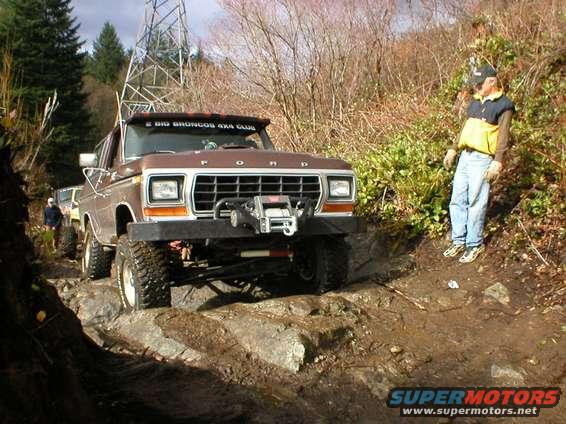 Brown 1978 Ford Bronco on a rocky trail with a person standing on the side