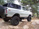 1978 Ford Bronco - A white 1978 Ford Bronco navigates a rocky trail, its off-road capabilities.