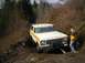 1978 Ford Bronco - A man watches as a 1978 Ford Bronco navigates a challenging, muddy off-road course.