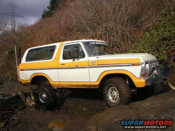 White and yellow 1978 Ford Bronco off-roading on muddy terrain
