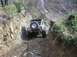 1978 Ford Bronco - A yellow jeep carefully maneuvers through a challenging off-road terrain with steep dirt banks on either side.