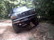 1996 Ford Bronco - Ford Bronco navigating a challenging off-road obstacle on a wooded trail.