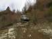 1978 Ford Bronco - A silver pickup truck navigates a challenging, off-road trail with dense vegetation on the slopes.