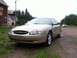 2000 Ford Taurus - A gold sedan is parked on a gravel road with a building and trees in the background.