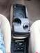 2000 Ford Taurus - The center console of a vehicle, cup holders and a storage area with sunglasses and a phone inside.