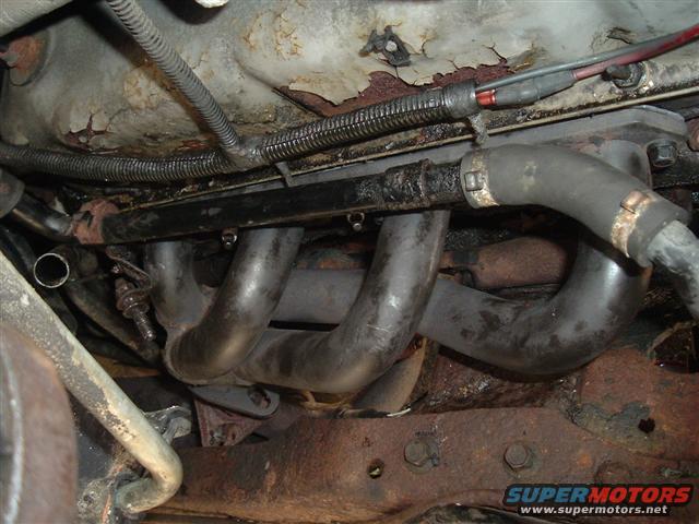 Exhaust manifold with hoses and wiring on rusty engine components
