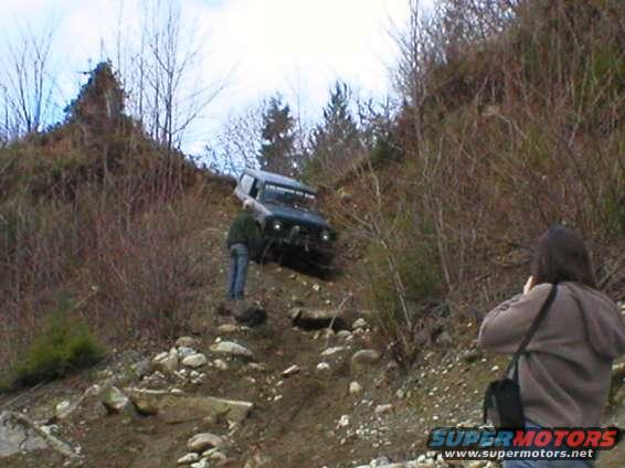 1978 Ford Bronco, dark blue, on a rocky hill with a person standing nearby