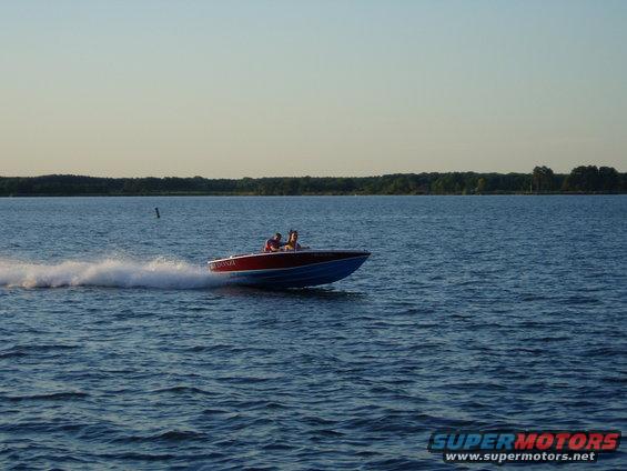 Speed boat with two people on board cutting through the water, leaving a wake