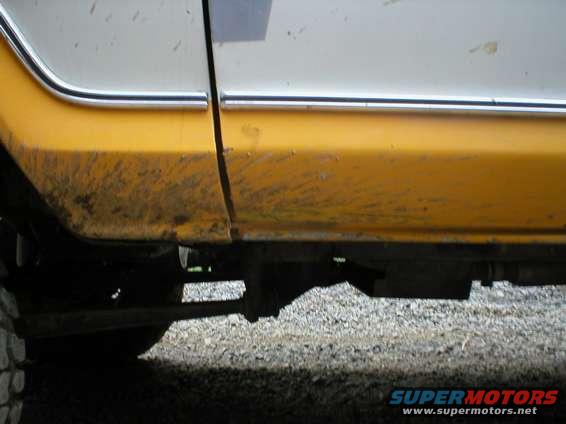 side panel and frame of a yellow and white vehicle covered in mud