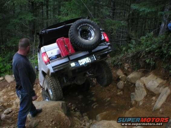 White Ford Bronco with a red gas can and spare tire on the back, angled on a rocky trail