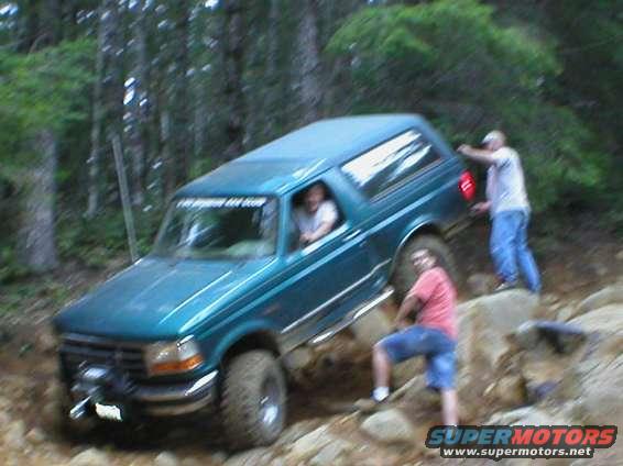 Teal 1995 Ford Bronco off-roading on rocky terrain