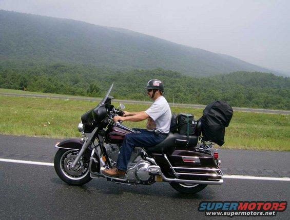 Man riding a motorcycle on a wet road with mountains in the background